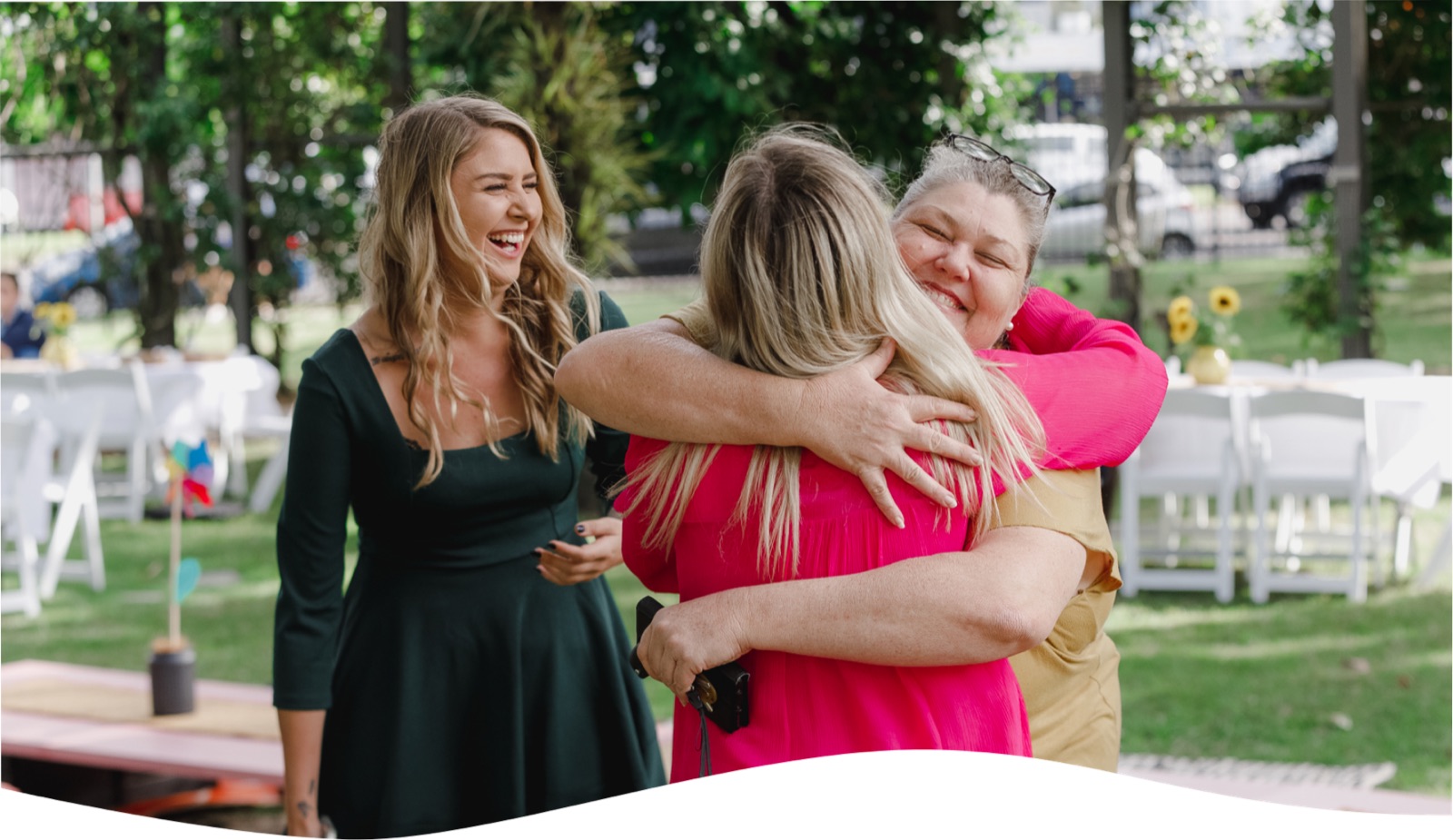 i'ara team members embracing and laughing together at a village gathering under the trees