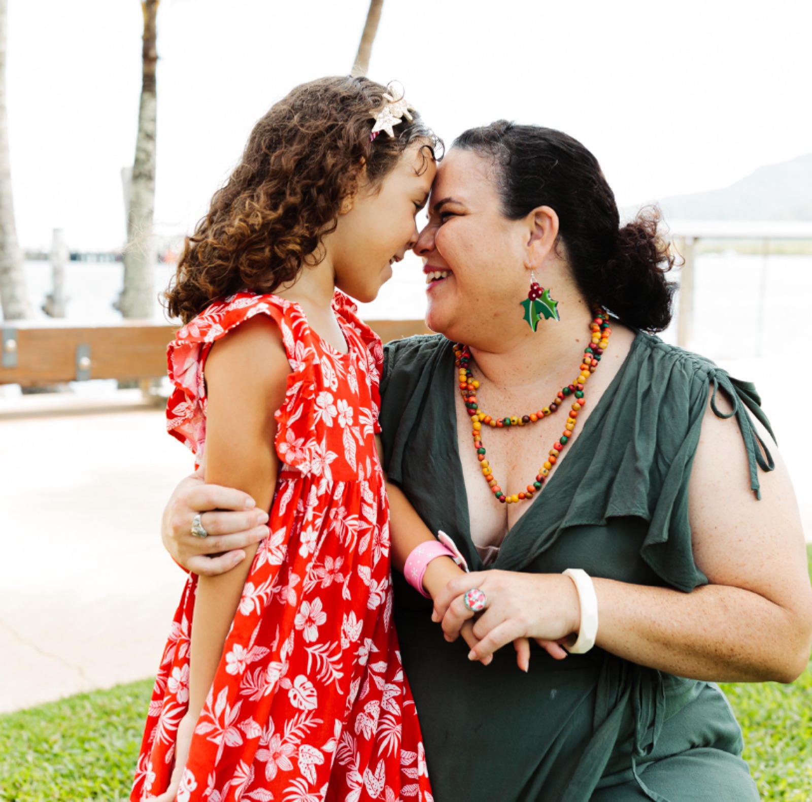 A mother and daughter from the i'ara community laughing forehead to forehead on the Cairns waterfront