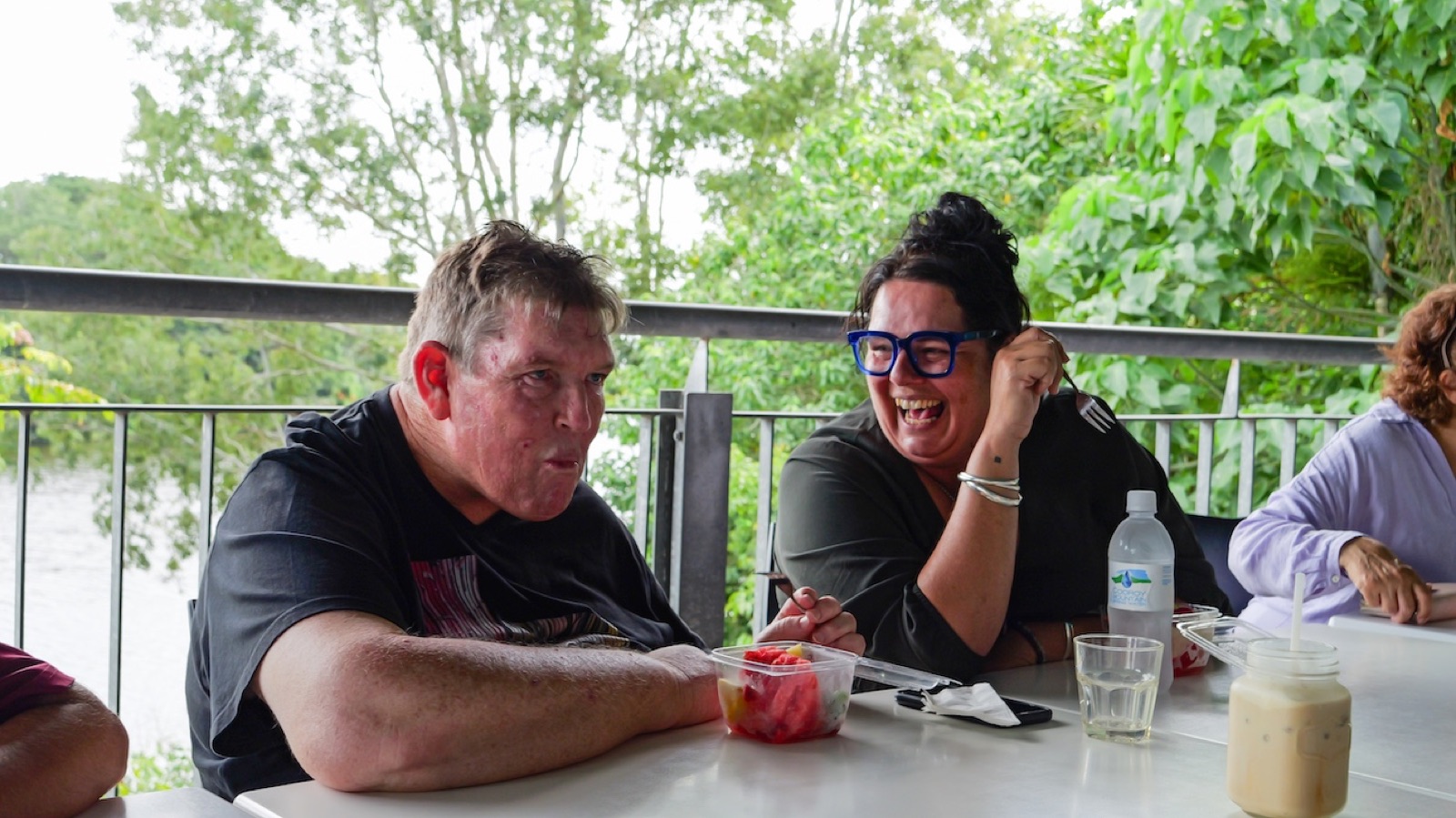 Two members of the i'ara community sharing a meal and a laugh outdoors in Far North Queensland