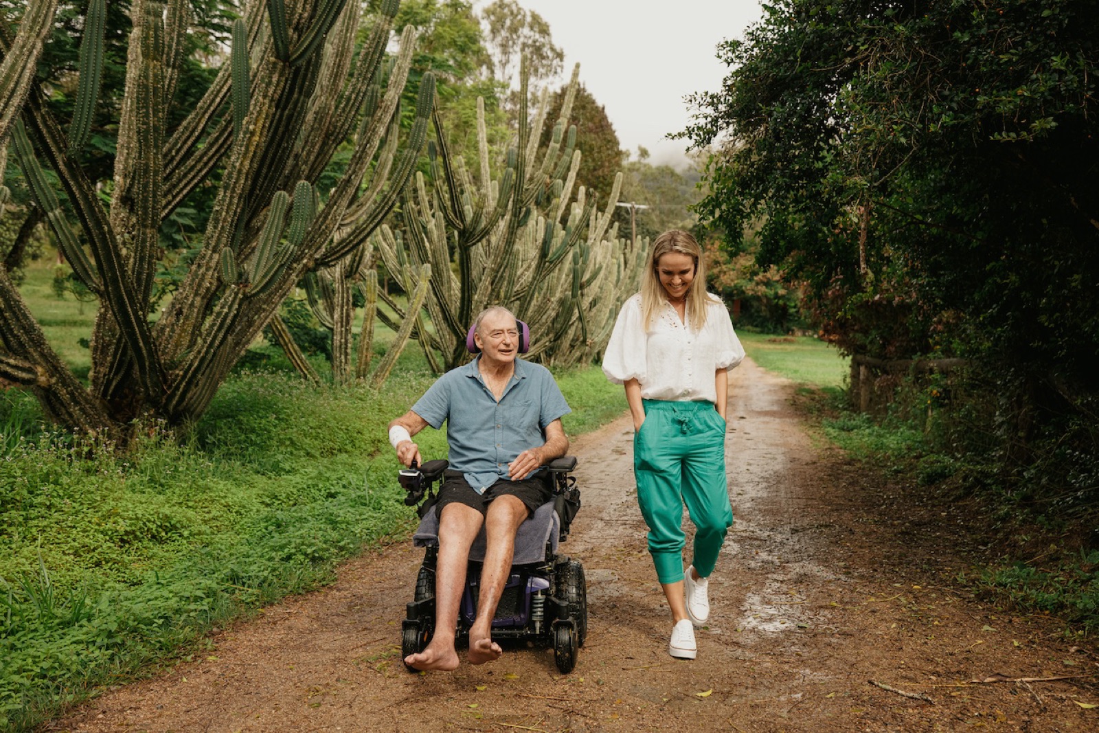 An i'ara participant in his power wheelchair sharing a laugh with his Support Coordinator on a Far North Queensland country track